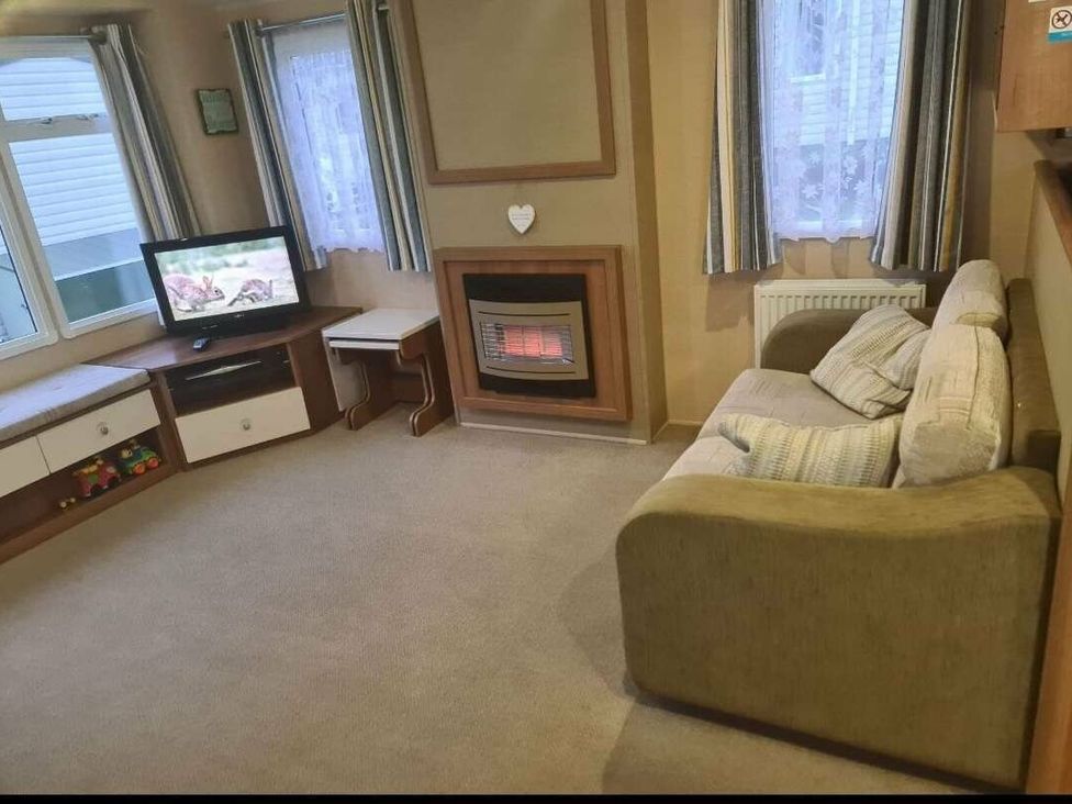 a living room with a sofa, TV, and fireplace at Littlesea Holiday Park - Holiday Accommodation 19270, Weymouth