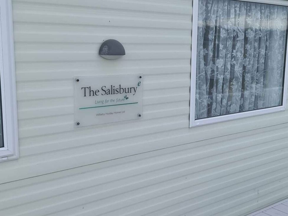 a sign for The Salisbury mounted on a white wall next to a window with curtains at Littlesea Holiday Park - Holiday Accommodation 19270 in Weymouth