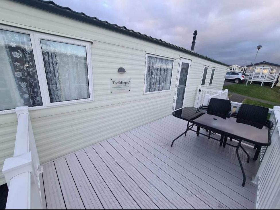 a deck area with a table and chairs outside a holiday home at Littlesea Holiday Park - Holiday Accommodation 19270 in Weymouth
