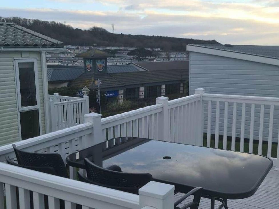 a deck with a black table and chairs overlooking a landscape at Littlesea Holiday Park - Holiday Accommodation 19270 in Weymouth