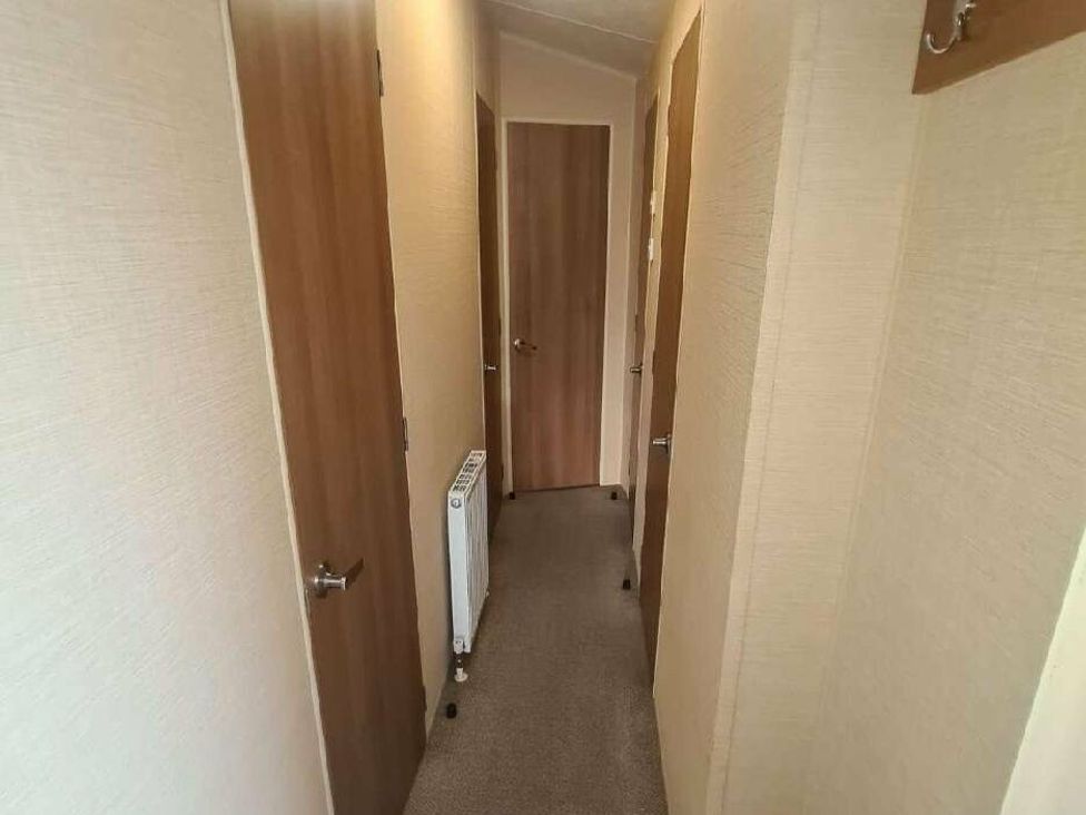 a hallway with several closed doors and a radiator at Littlesea Holiday Park - Holiday Accommodation 19270, Weymouth