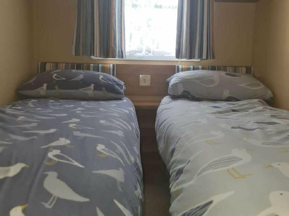 two single beds with bird-patterned bedding in a room at Littlesea Holiday Park - Holiday Accommodation 19270, Weymouth