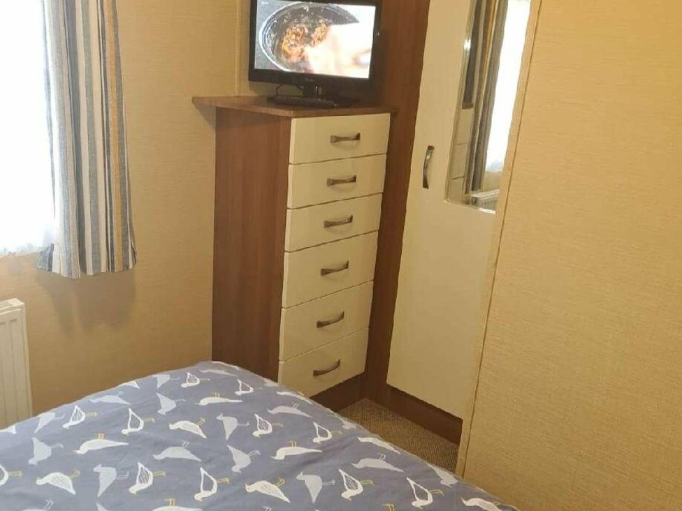 a bedroom with a chest of drawers and a television at Littlesea Holiday Park - Holiday Accommodation 19270 in Weymouth