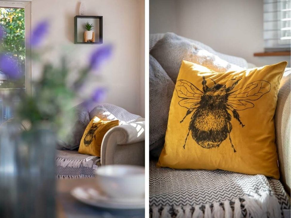 a sofa with a bee-printed cushion and a blurred vase of flowers at Florida Keys Holiday Park - Holiday Accommodation 19291, York