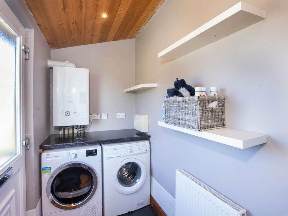 a laundry room with a washing machine and dryer, wall shelves, and a radiator at Florida Keys Holiday Park - Holiday Accommodation 19291, York