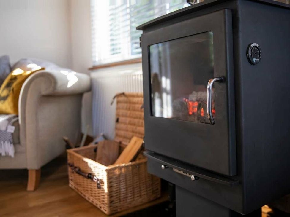 a black wood stove with a visible fire and a woven basket of wood at Florida Keys Holiday Park - Holiday Accommodation 19291, York