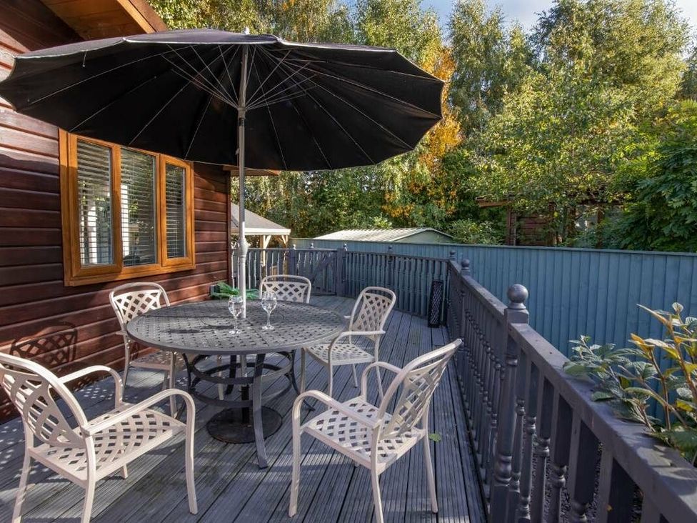 a deck area with a table and chairs under a black umbrella at Florida Keys Holiday Park - Holiday Accommodation 19291, York