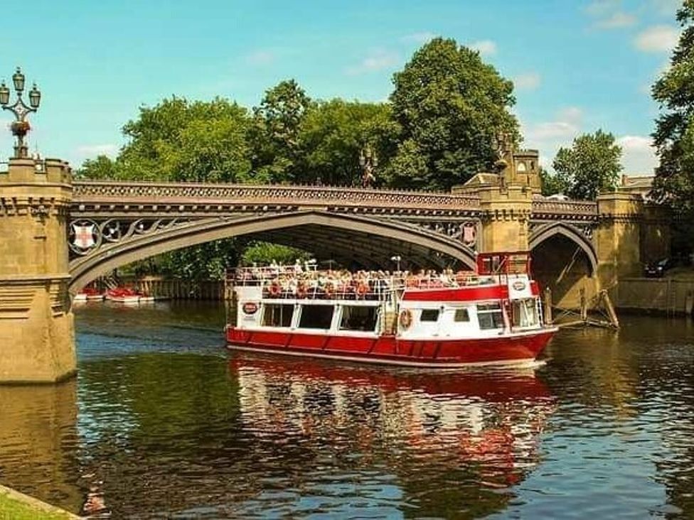 a riverboat passing under a stone bridge with trees along the banks at Florida Keys Holiday Park - Holiday Accommodation 19291, York
