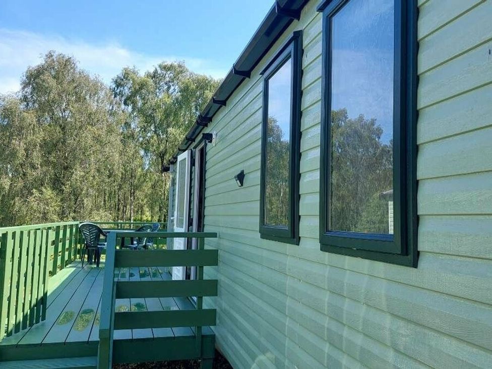 a green exterior of a building with windows and a deck at Hunters Quay Holiday Village - Holiday Accommodation 19798, Dunoon