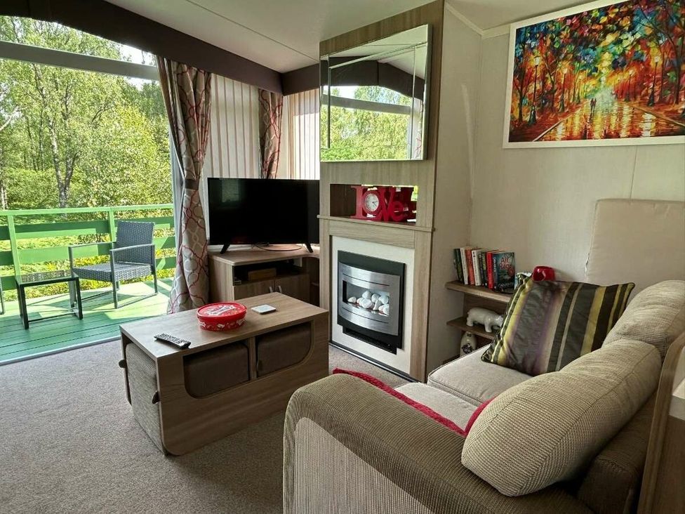 a living room with a television, a fireplace, and a sofa at Hunters Quay Holiday Village - Holiday Accommodation 19798, Dunoon