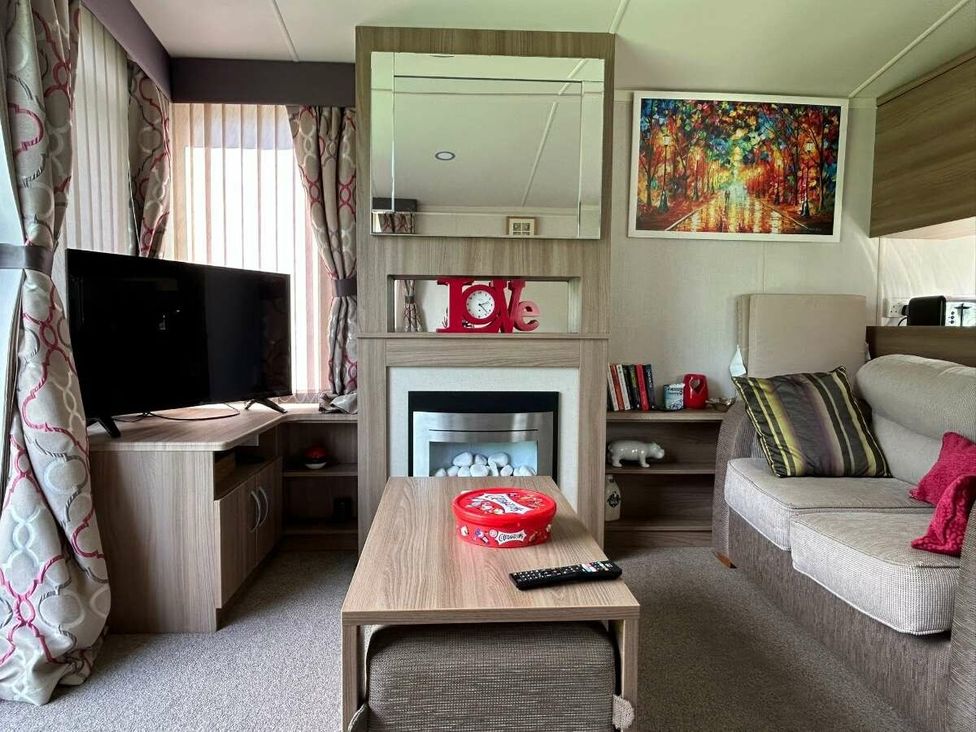 a living room with a television, fireplace, and seating area at Hunters Quay Holiday Village - Holiday Accommodation 19798, Dunoon