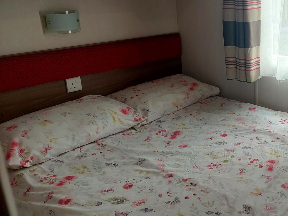 A bedroom with a bed and floral sheets at Hunters Quay Holiday Village in Dunoon