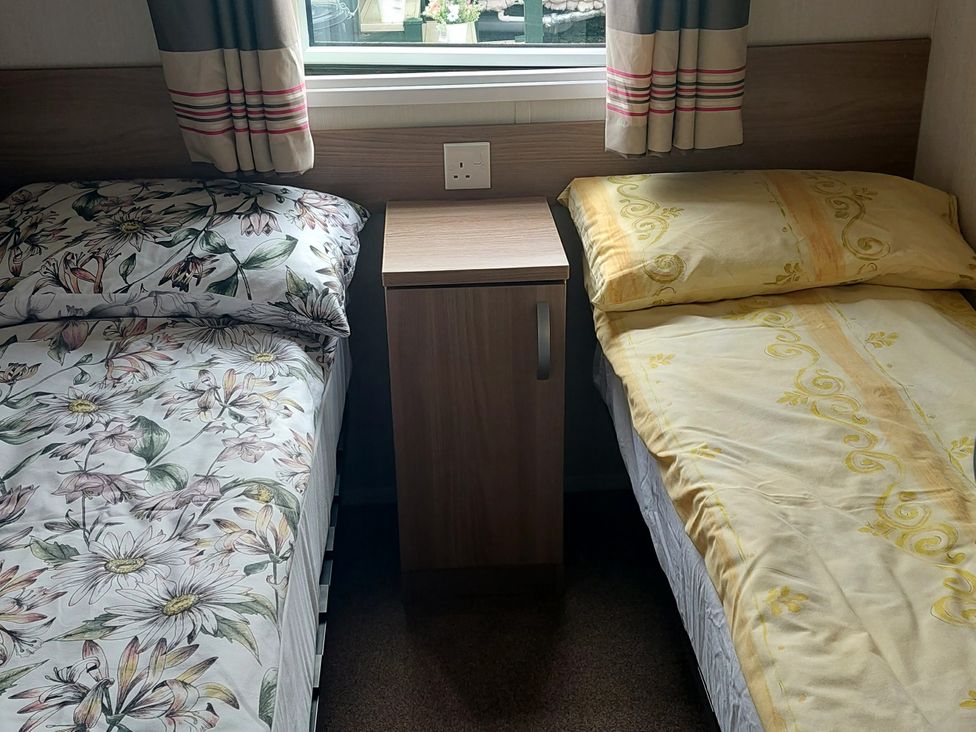 A bedroom with two beds and a bedside table at Hunters Quay Holiday Village in Dunoon