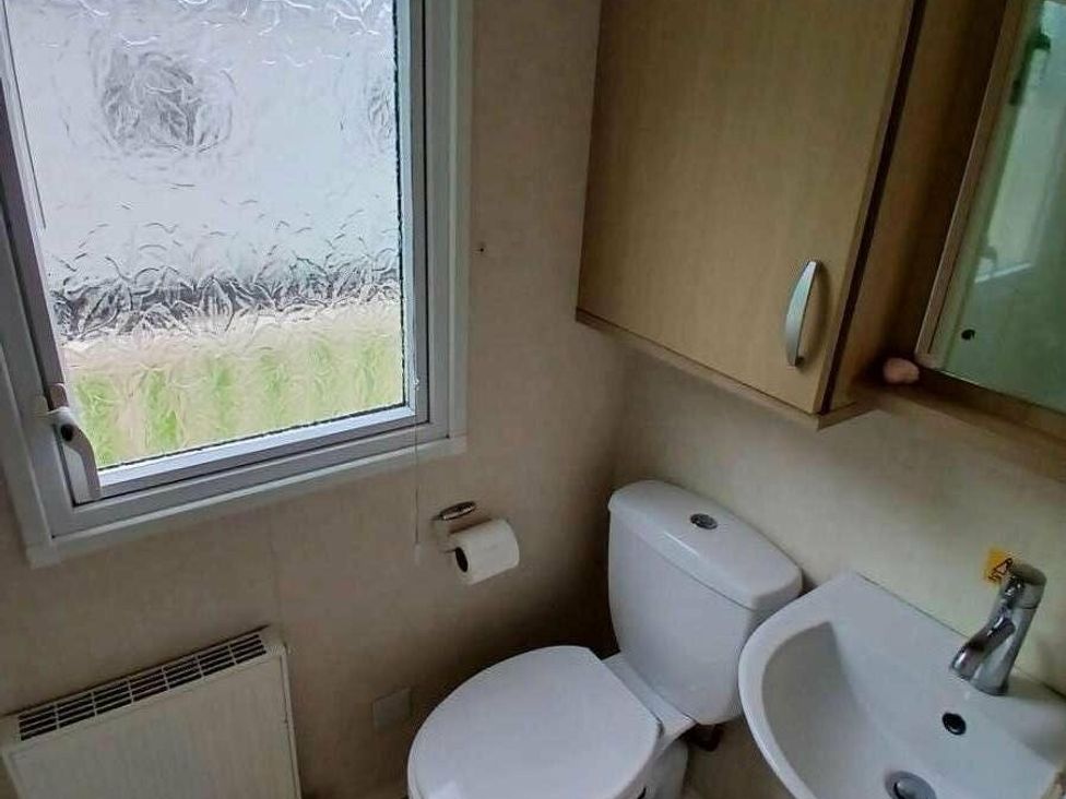 a bathroom with a toilet, sink, and window at Hoburne Cotswolds - Holiday Accommodation 20158 in South Cerney