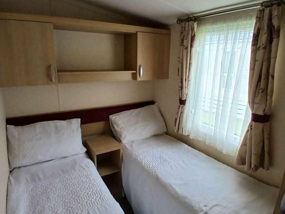 a bedroom with two single beds and a window with sheer curtains at Hoburne Cotswolds - Holiday Accommodation 20158 in South Cerney