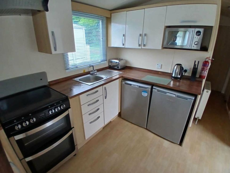 a kitchen with cabinets, sink, stove, microwave, and two refrigerators at Hoburne Cotswolds - Holiday Accommodation 20158 South Cerney