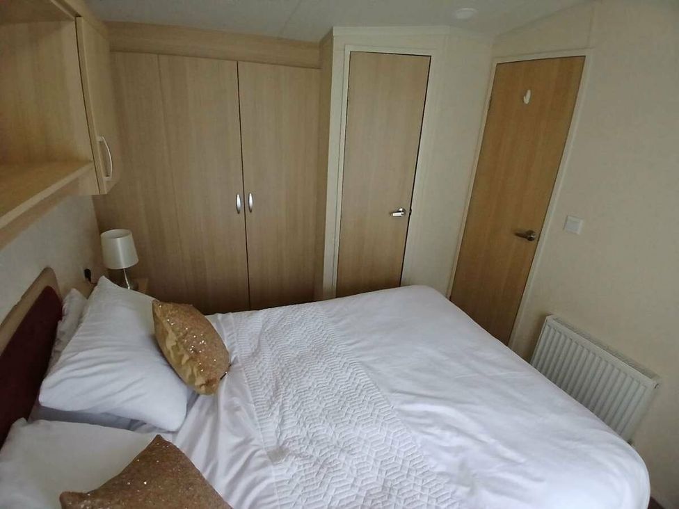 a bedroom with a bed, wardrobe, and door at Hoburne Cotswolds - Holiday Accommodation 20158 South Cerney