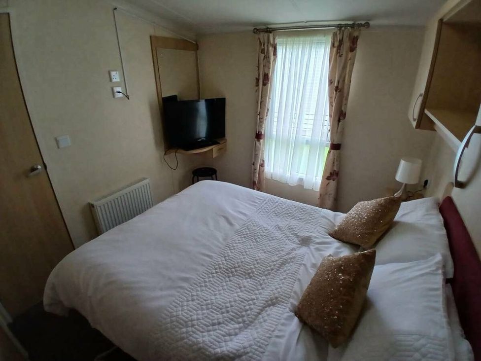 a bedroom with a bed, television, and curtains at Hoburne Cotswolds - Holiday Accommodation 20158, South Cerney