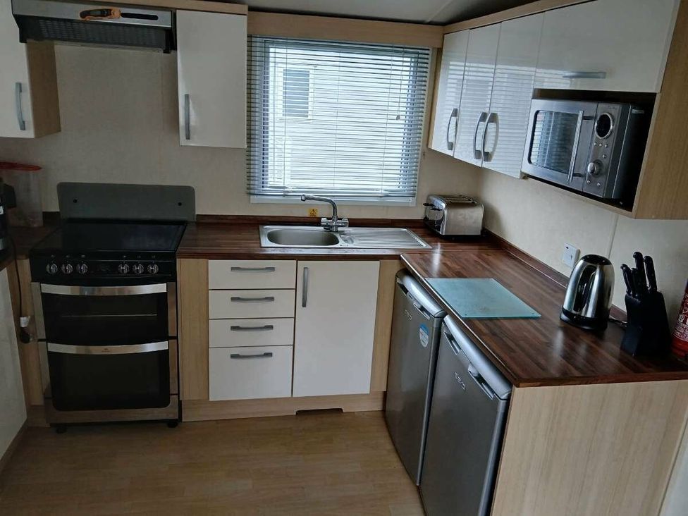 a kitchen with cabinets, a sink, stove, microwave, and refrigerator at Hoburne Cotswolds - Holiday Accommodation 20158 South Cerney