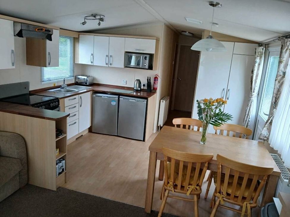 a kitchen and dining area with appliances and a table at Hoburne Cotswolds - Holiday Accommodation 20158 in South Cerney