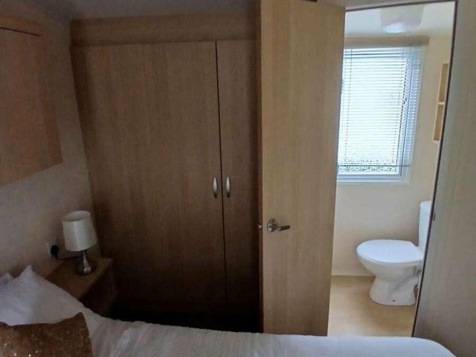 a bedroom with a wardrobe and a door leading to a bathroom at Hoburne Cotswolds - Holiday Accommodation 20158 in South Cerney