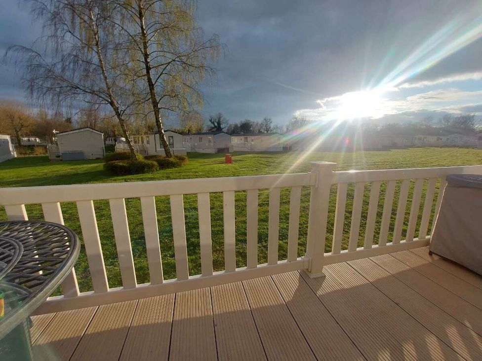 a view from a deck with a sunlit landscape and caravans at Hoburne Cotswolds - Holiday Accommodation 20158 South Cerney
