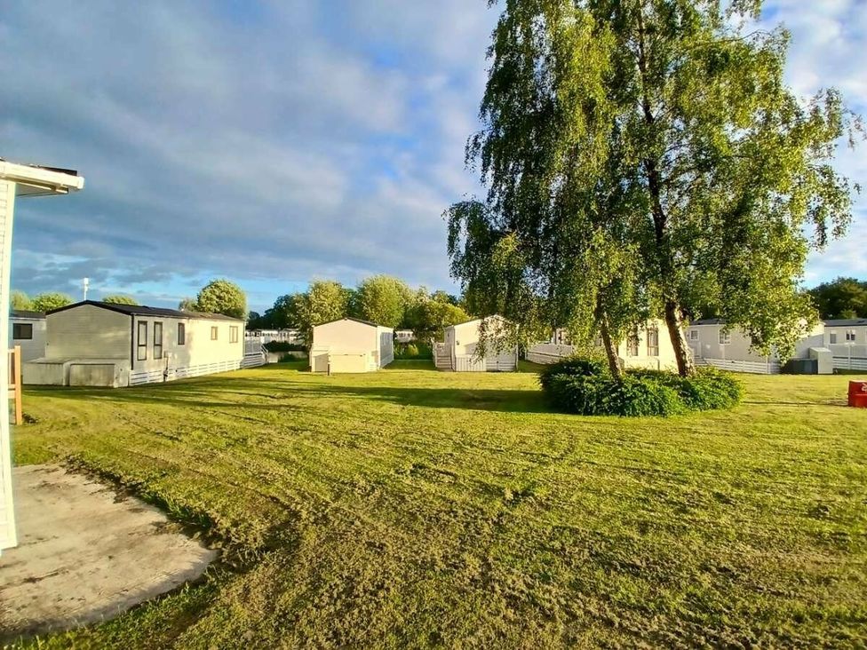 a grassy area with mobile homes and a tree at Hoburne Cotswolds - Holiday Accommodation 20158 in South Cerney