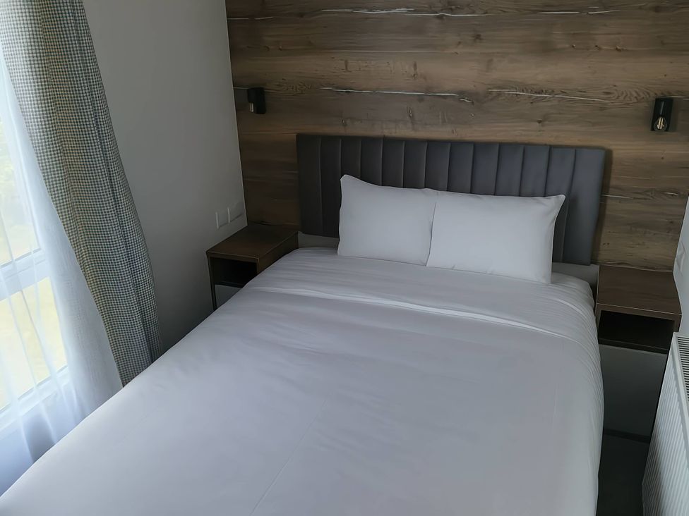 A bedroom with a bed and bedside table at Lakeland Leisure Park - Holiday Accommodation 20349, Grange-Over-Sands