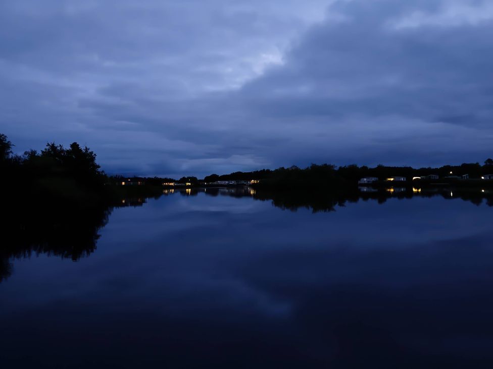 A view of a lake with reflections and lights at Lakeland Leisure Park - Holiday Accommodation 20349 in Grange-Over-Sands