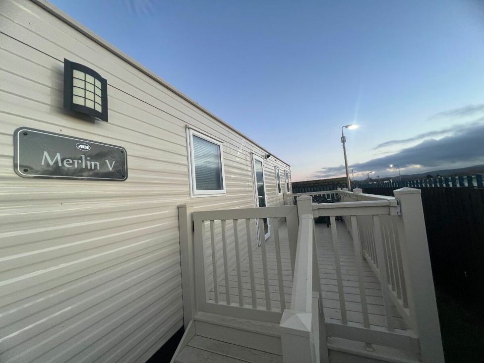 a mobile home with a sign reading Merlin V and a deck at Golden Sands Kinmel Bay - Holiday Accommodation 20528 Rhyl
