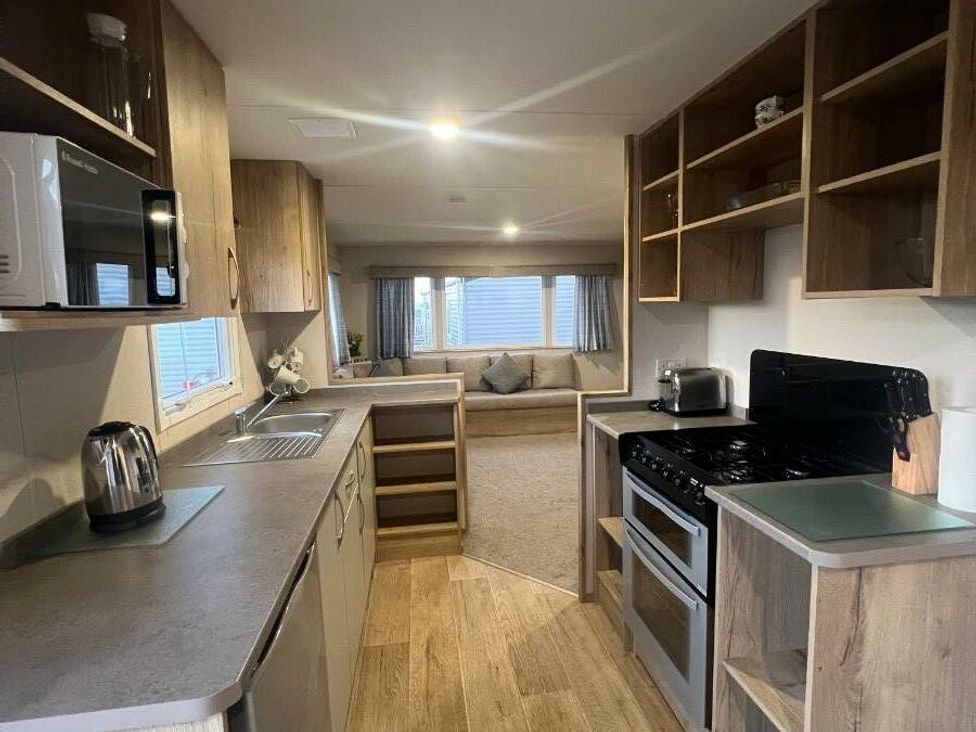 a kitchen area with cabinets, a stove, and a microwave at Golden Sands Kinmel Bay - Holiday Accommodation 20528 in Rhyl