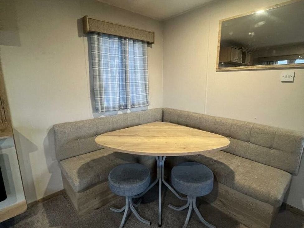 a dining area with a triangular table and cushioned seating at Golden Sands Kinmel Bay - Holiday Accommodation 20528 in Rhyl