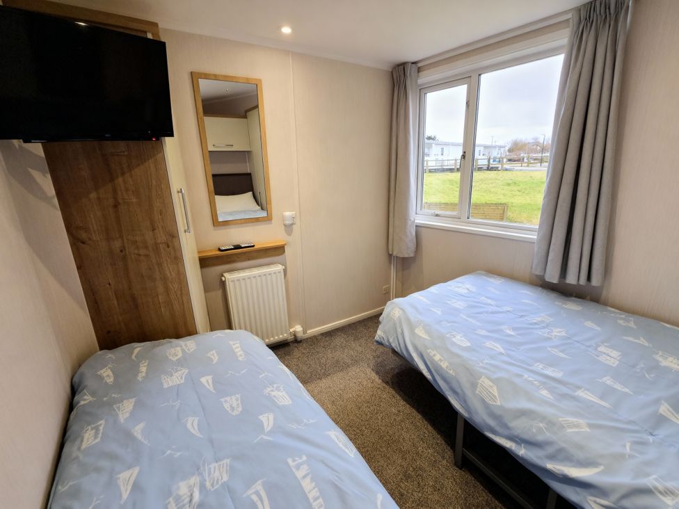 A bedroom with two single beds and a television at Thornwick Bay Holiday Village - Holiday Accommodation 20633, Flamborough