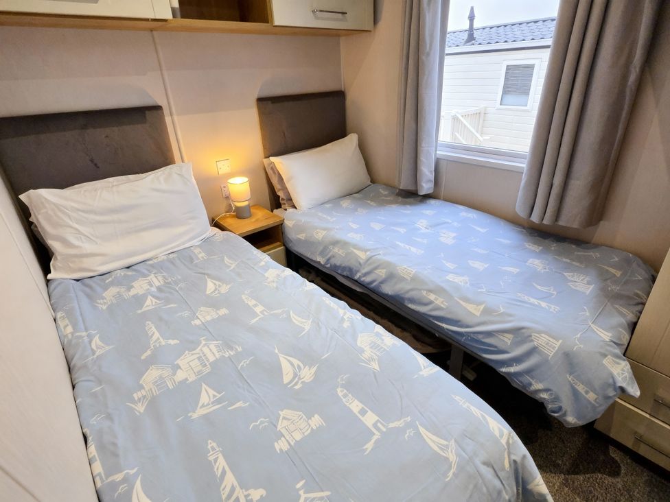 A bedroom with two single beds and a bedside table at Thornwick Bay Holiday Village - Holiday Accommodation 20633, Flamborough