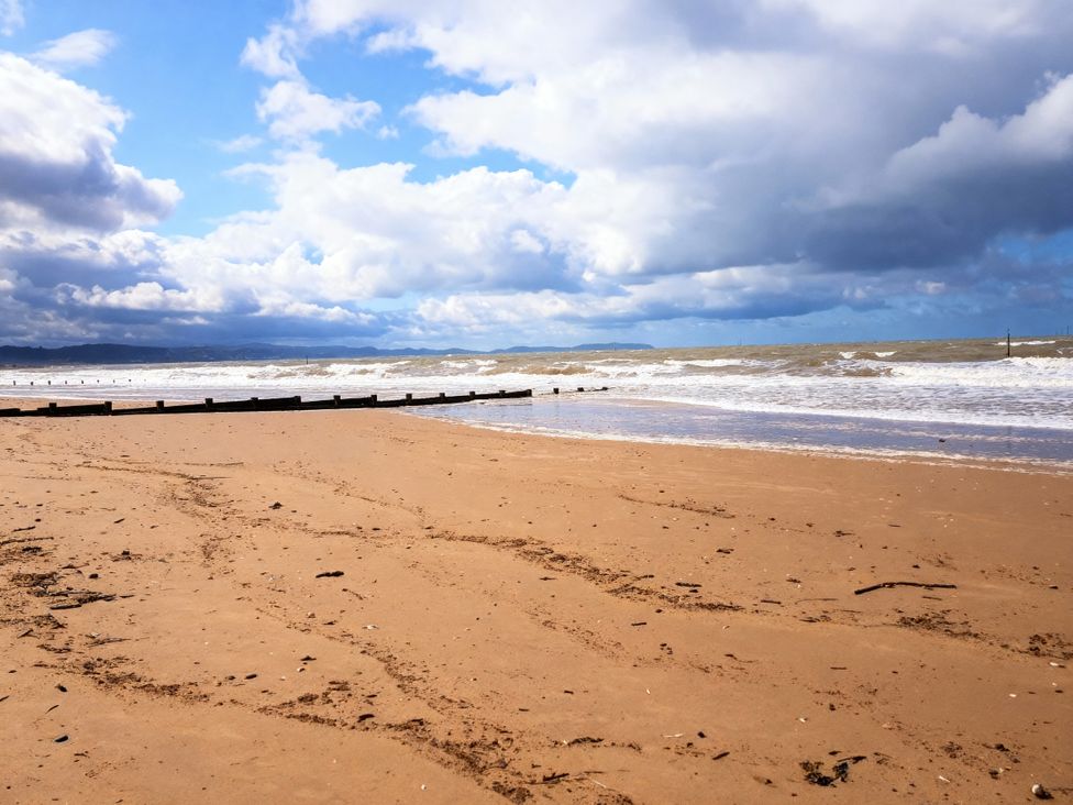 A beach with waves hitting the shore and wooden posts at Lyons Robin Hood - Holiday Accommodation 20871 Rhyl