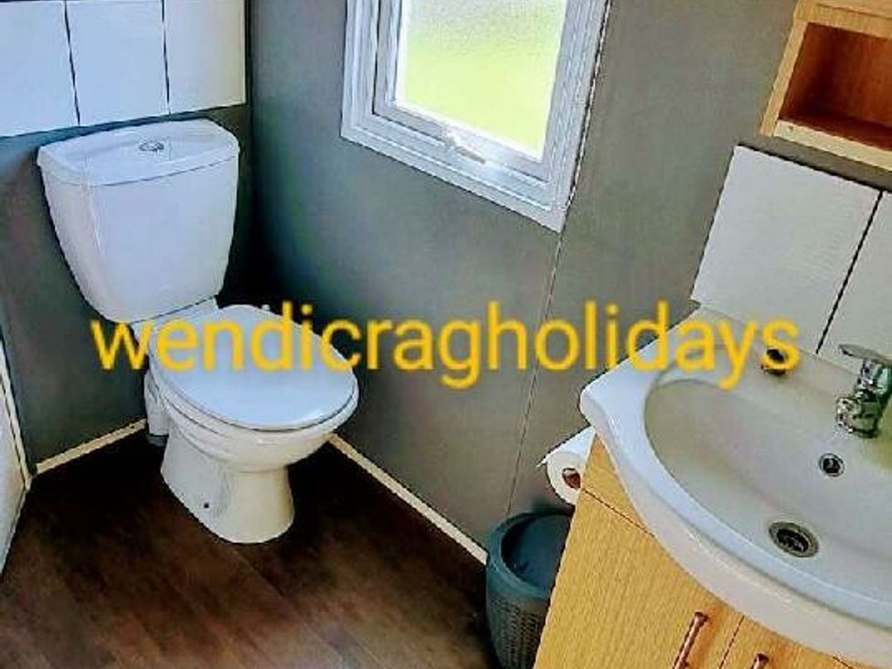 a bathroom with a toilet, sink, and window at Ty Mawr Holiday Park - Holiday Accommodation 20936 Towyn
