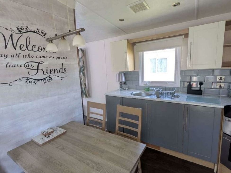 a kitchen area with a table and chairs, a sink, and cabinets at Ty Mawr Holiday Park - Holiday Accommodation 20936 in Towyn