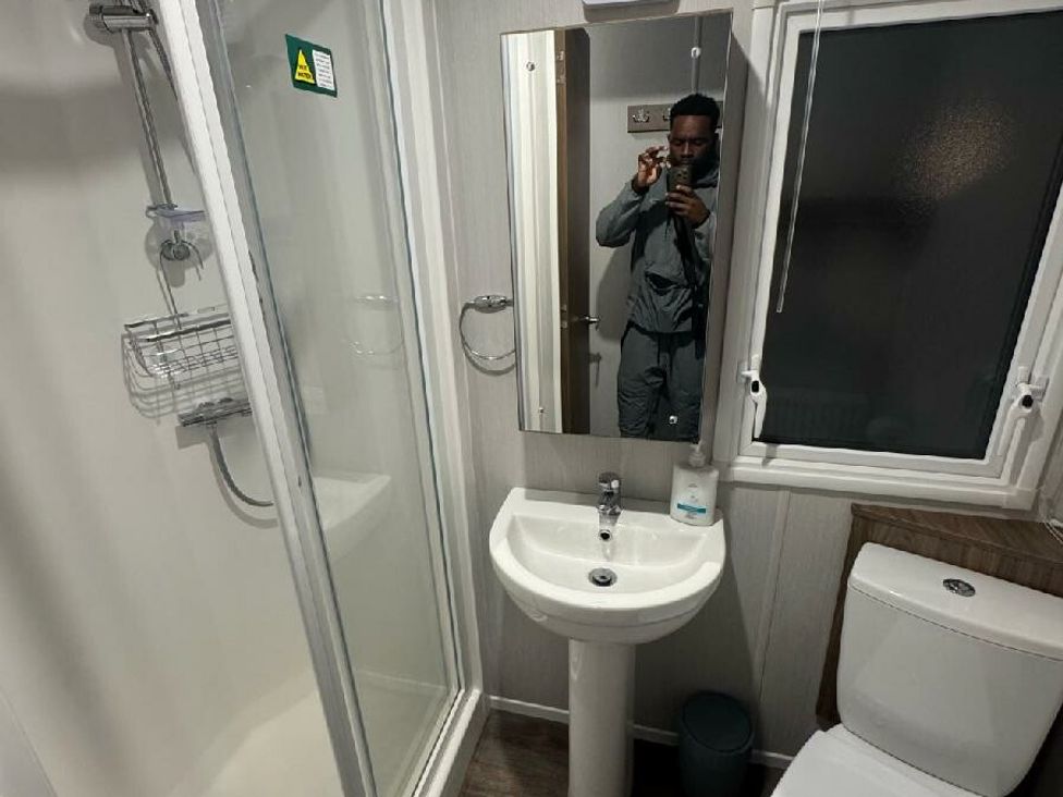 a bathroom with a shower, sink, mirror, and toilet at Butlins Skegness - Holiday Accommodation 21028 Skegness