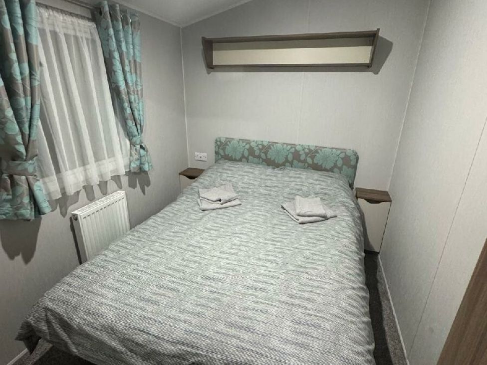 a bedroom with a double bed and floral-patterned bedding at Butlins Skegness - Holiday Accommodation 21028 in Skegness