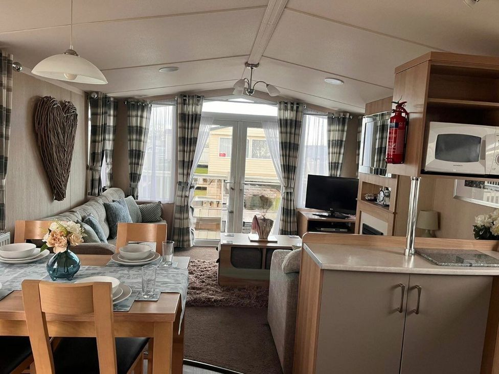 a living room and kitchen area with a table set for dining at Eastgate Caravan Park - Holiday Accommodation 21087 in Ingoldmells