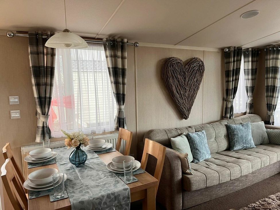 a dining area with a table set for four and a sofa in a living room at Eastgate Caravan Park - Holiday Accommodation 21087 in Ingoldmells