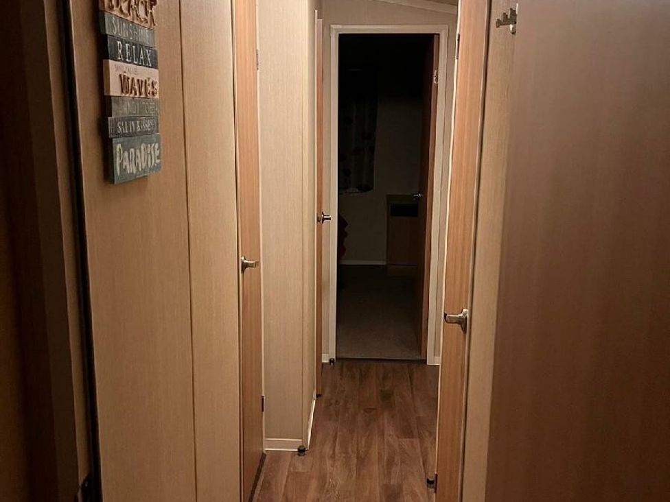 a hallway with wooden paneling and doors on either side at Eastgate Caravan Park - Holiday Accommodation 21087 in Ingoldmells