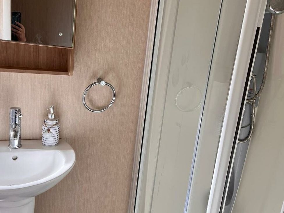 a bathroom with a sink, mirror, and shower at Eastgate Caravan Park - Holiday Accommodation 21087 in Ingoldmells