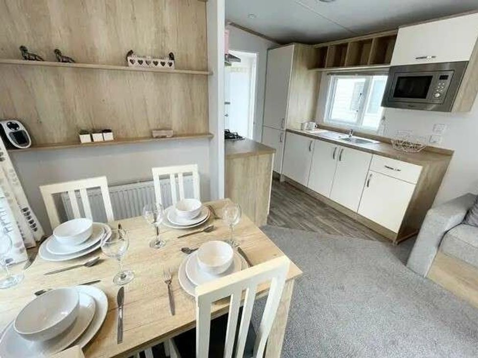 a kitchen and dining area with a table set for four at Trevella Park - Holiday Accommodation 21105 Crantock