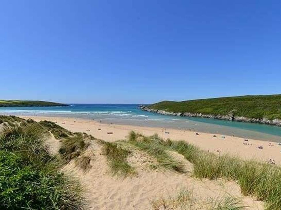 a beach with sand and water surrounded by greenery at Trevella Park - Holiday Accommodation 21105 in Crantock