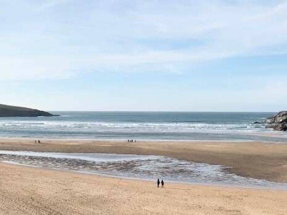 a beach with water and people walking on the sand at Trevella Park - Holiday Accommodation 21105 in Crantock