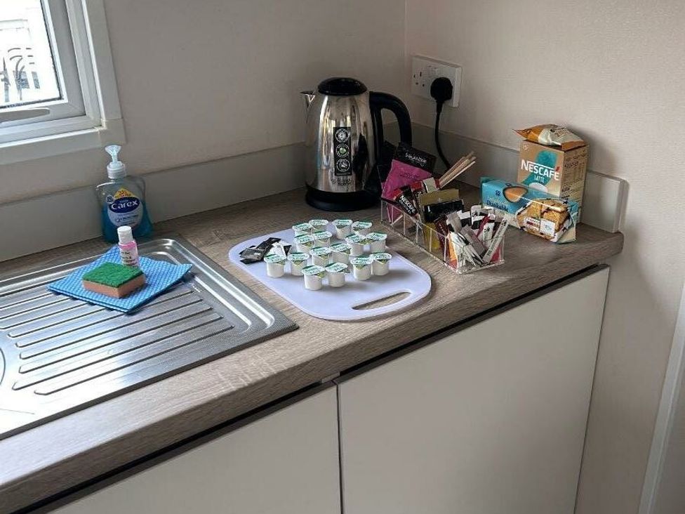 a kitchen counter with a kettle, cleaning supplies, coffee packets, and creamers at Cala Gran Holiday Park - Holiday Accommodation 21106 in Fleetwood