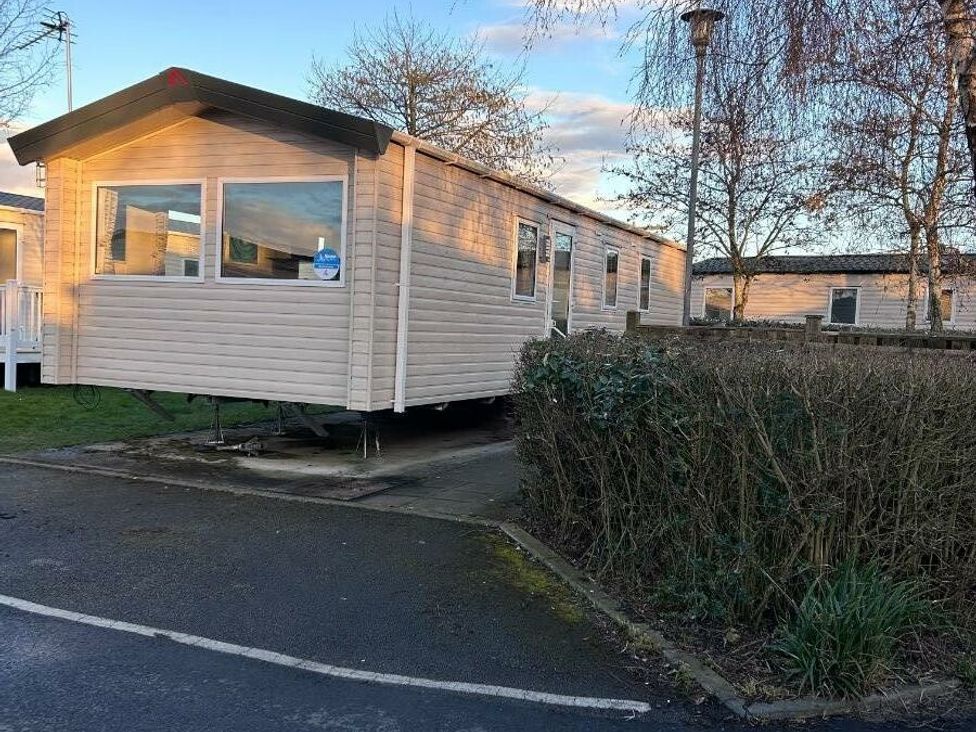 a holiday home parked on a lot with shrubs and trees at Cala Gran Holiday Park - Holiday Accommodation 21106 Fleetwood