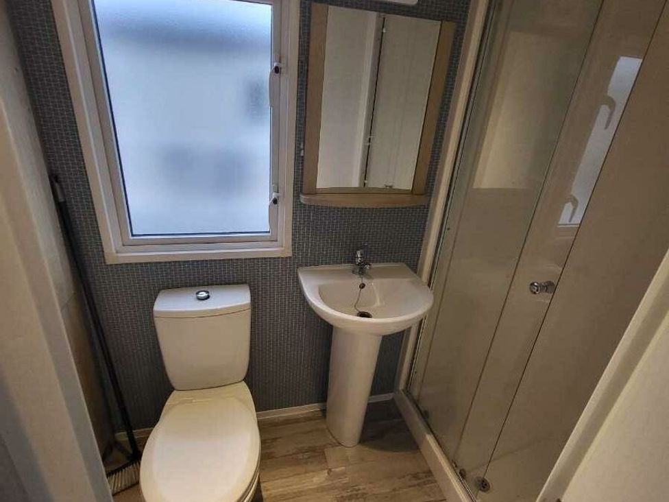 a bathroom with a toilet, sink, mirror, and shower enclosure at Ty Mawr Holiday Park - Holiday Accommodation 21121 in Ty Mawr