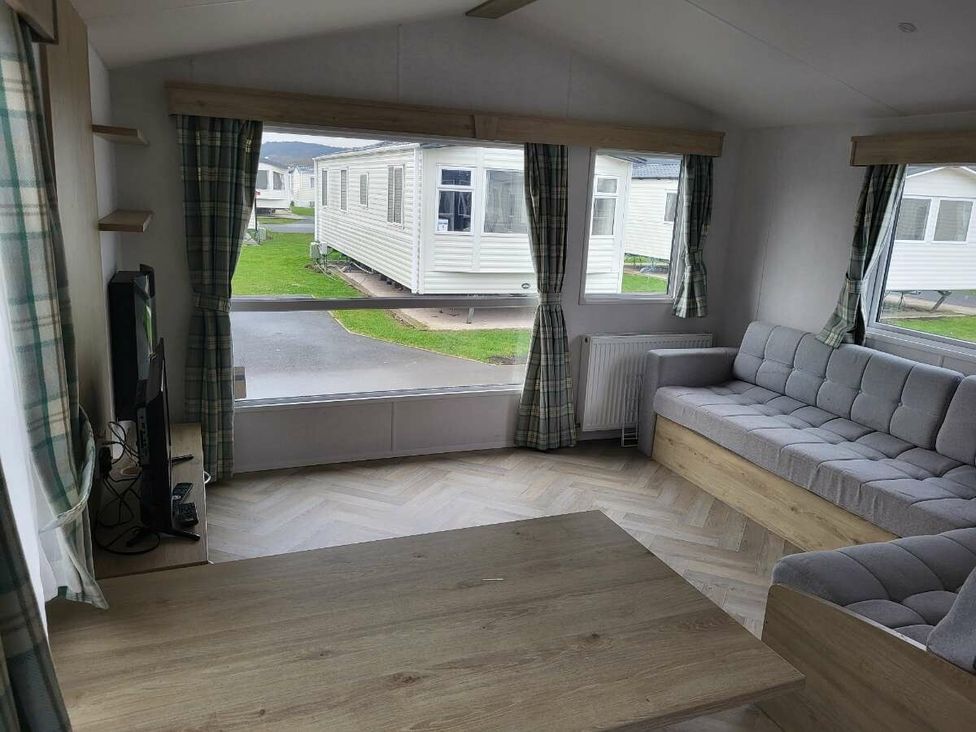 a living room with a gray sofa and large windows at Ty Mawr Holiday Park - Holiday Accommodation 21121, Ty Mawr